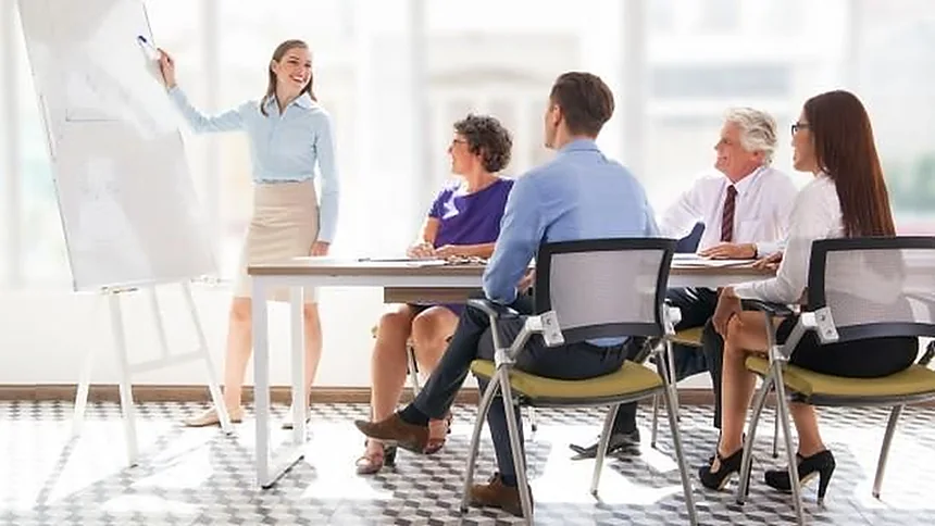 Formadora ante una pizarra con un grupo de personas sentadas