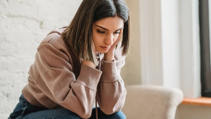 Mujer sentada con las manos juntas, pensativa
