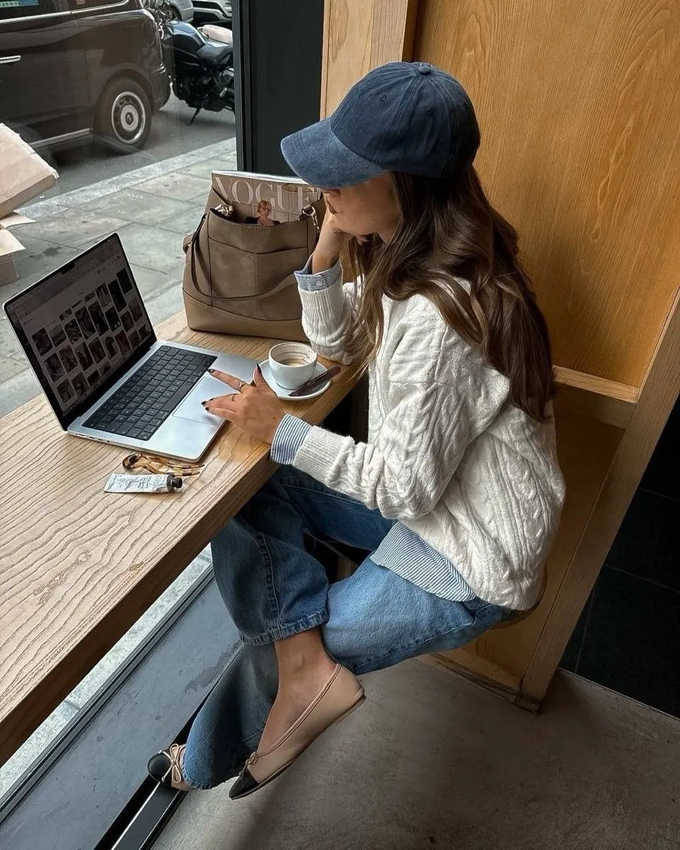 Mujer trabajando con un portátil y un café junto a un ventanal